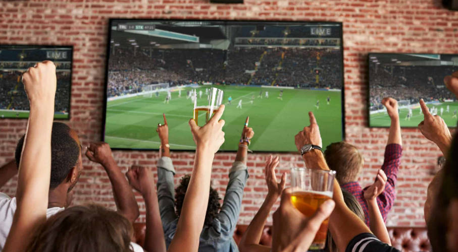 A group of people cheering at a sports bar.